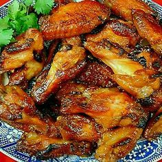 chicken wings with cilantro and parsley in a blue and white plate on a red tablecloth