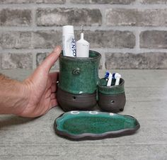 a hand is holding a toothbrush holder with two toothpaste holders in it