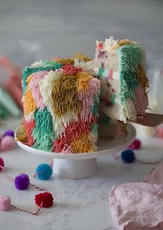 a cake that has been decorated with multicolored icing and pom - poms