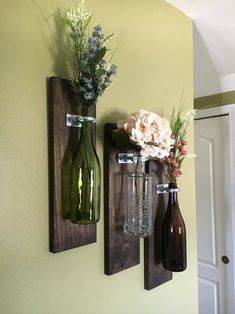 two vases with flowers are hanging on the wall