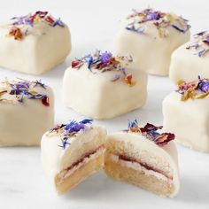 several pieces of cake with white frosting and purple flowers on them are cut in half