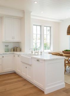 a kitchen with white cabinets and an island in the middle is shown, along with a dining room table