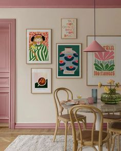 a dining room with pink walls and pictures on the wall