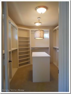 an empty walk in closet with white cabinets and lights hanging from it's ceiling