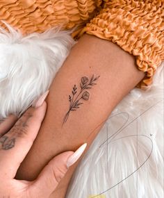 a woman's arm with a small flower tattoo on the left side of her leg