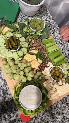 a wooden cutting board topped with lots of different types of vegetables and dip sauces