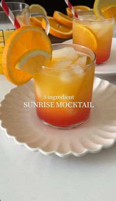 two glasses filled with orange juice sitting on top of a white plate next to an orange slice