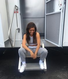 a woman sitting in the back of a trailer with her hands on her knees and smiling