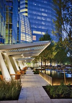 an outdoor area with tables and chairs next to a large glass building in the background