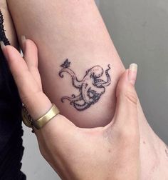 a woman's arm with a tattoo on it and an octopus in the shape of a heart