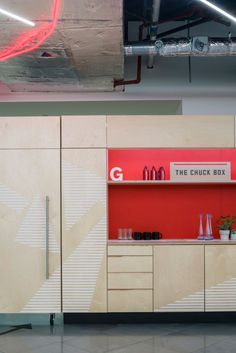 a red and white cabinet next to a wall with some bottles on the shelf in front of it