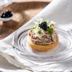 an appetizer on a glass plate with blackberries and other food items in the background