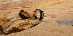 two wedding rings sitting on top of a piece of driftwood