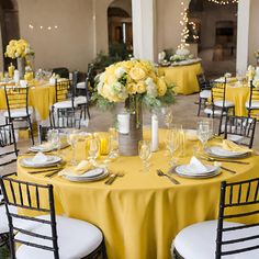 the tables are set with yellow linens and silverware for an elegant wedding reception