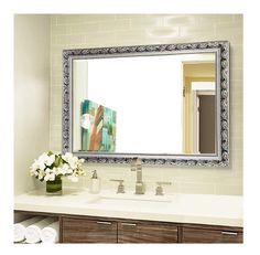 a bathroom vanity with a large mirror above it and flowers in a vase on the counter