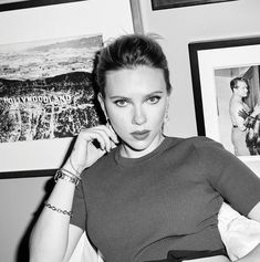 a black and white photo of a woman posing in front of pictures on the wall