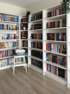 a room filled with lots of books on top of white shelving unit units next to a wooden floor