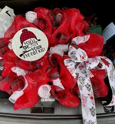 a close up of a red wreath on the back of a car with ribbon around it