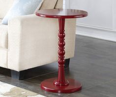 a red table sitting on top of a wooden floor next to a white couch in a living room