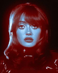 a woman with long hair and red light on her face is looking at the camera