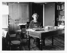 an old black and white photo of a woman sitting at a desk