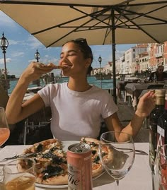 a woman eating pizza and drinking wine at an outdoor table by the water in venice, italy