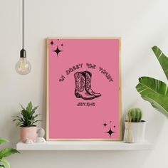 a pink poster with cowboy boots on it next to potted plants and a light bulb