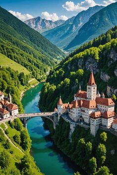 an aerial view of a castle in the middle of a valley with green trees and mountains behind it