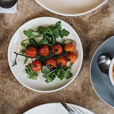 a table topped with white plates filled with food and utensils on top of it