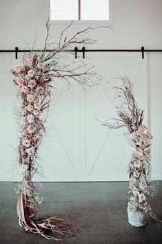 two tall vases with flowers and branches in them