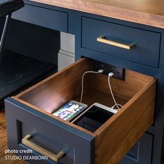 an iphone charging in a drawer under a desk