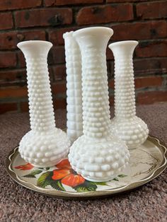 three white vases sitting on top of a plate