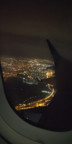 an airplane wing at night with the city lights seen through it's window, taken from above