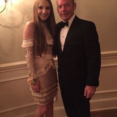 a man in a tuxedo standing next to a woman wearing a short dress