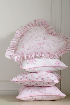 pillows stacked on top of each other in front of a white door with pink flowers