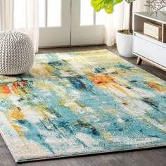 a blue and yellow area rug with an abstract design on the floor in front of a window