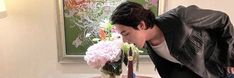 a man leaning over a table with flowers on it