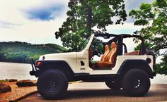 a white jeep is parked by the water