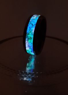 "Meet the Big Bang in a Ring! We used real crushed Coastal Opal and actual Meteorite fragments and combined them with UV-sensitive powder to make this one-of-a-kind, unique, and vibrant glow ring! This ring holds it all! Crushed Blue Coastal Opal and shavings from a Meteorite on a Tungsten Insert! Who knows how far this meteor traveled in its astroid form before making contact with our third rock! This style is perfect for kids, teens, and adults as it is available in a variety of sizes and widt Luminous Ring Jewelry As A Gift, Luminous Ring Jewelry For Gifts, Green Luminous Round Jewelry, Glow In The Dark Black Jewelry For Gift, Dark Ring, Cosmic Ring, Dark Rings, Galaxy Ring, Meteorite Ring