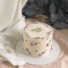 a white cake sitting on top of a plate next to a flower covered table cloth