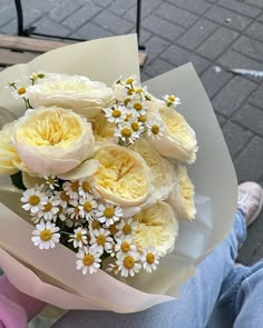 a bouquet of white and yellow flowers sitting on top of a person's lap