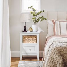 a bedroom with a bed, nightstand and lamp on the side table in front of the window