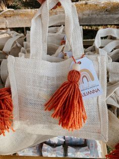 an orange tasseled bag hanging from a wooden rack with other bags in the background