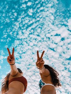 two women in bikinis making peace signs with their hands