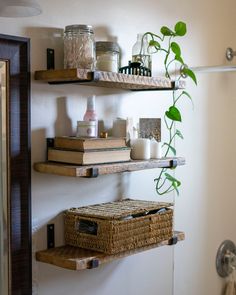 two shelves with baskets and candles on them in a bathroom next to a shower stall