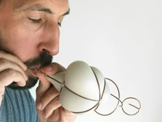 a man is blowing on an object with his mouth and nose as he looks at it