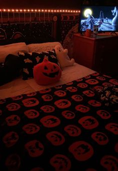 a bed with a black and red bedspread that has pumpkins on it