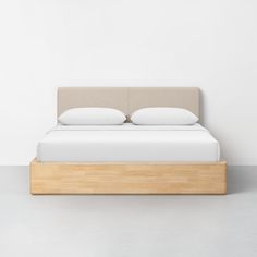 a bed with two pillows on top of it and a wooden frame in the middle