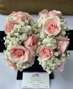 pink roses and white baby's breath are arranged in a black vase on a table