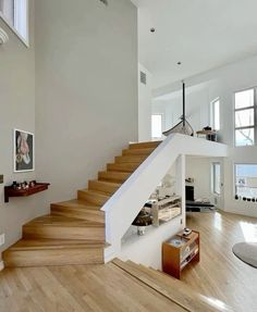 there is a stair case in the middle of this living room with hardwood floors and white walls